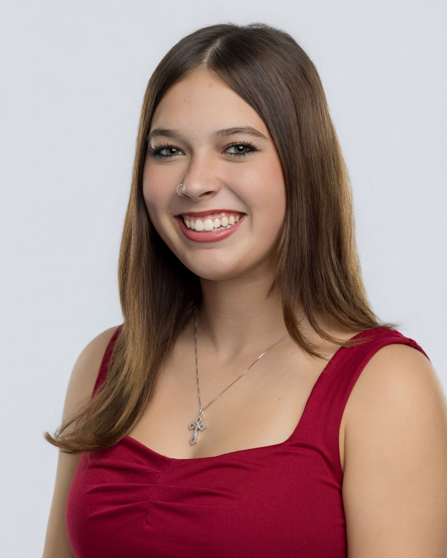 Woman in red sleeveless top smiling against white background.
