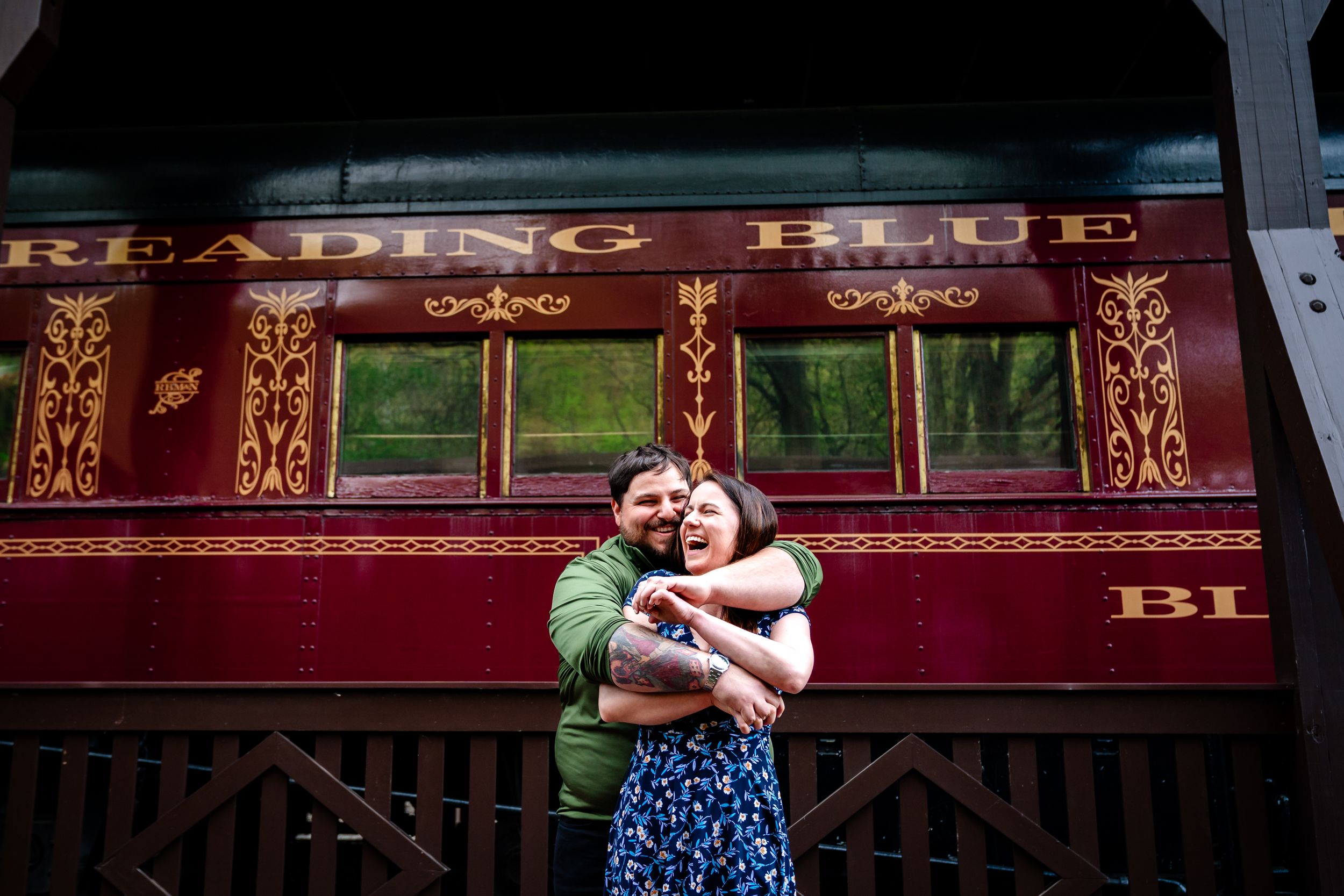 A couple dances together on a vintage red train car in a romantic moment during their engagement photo session.