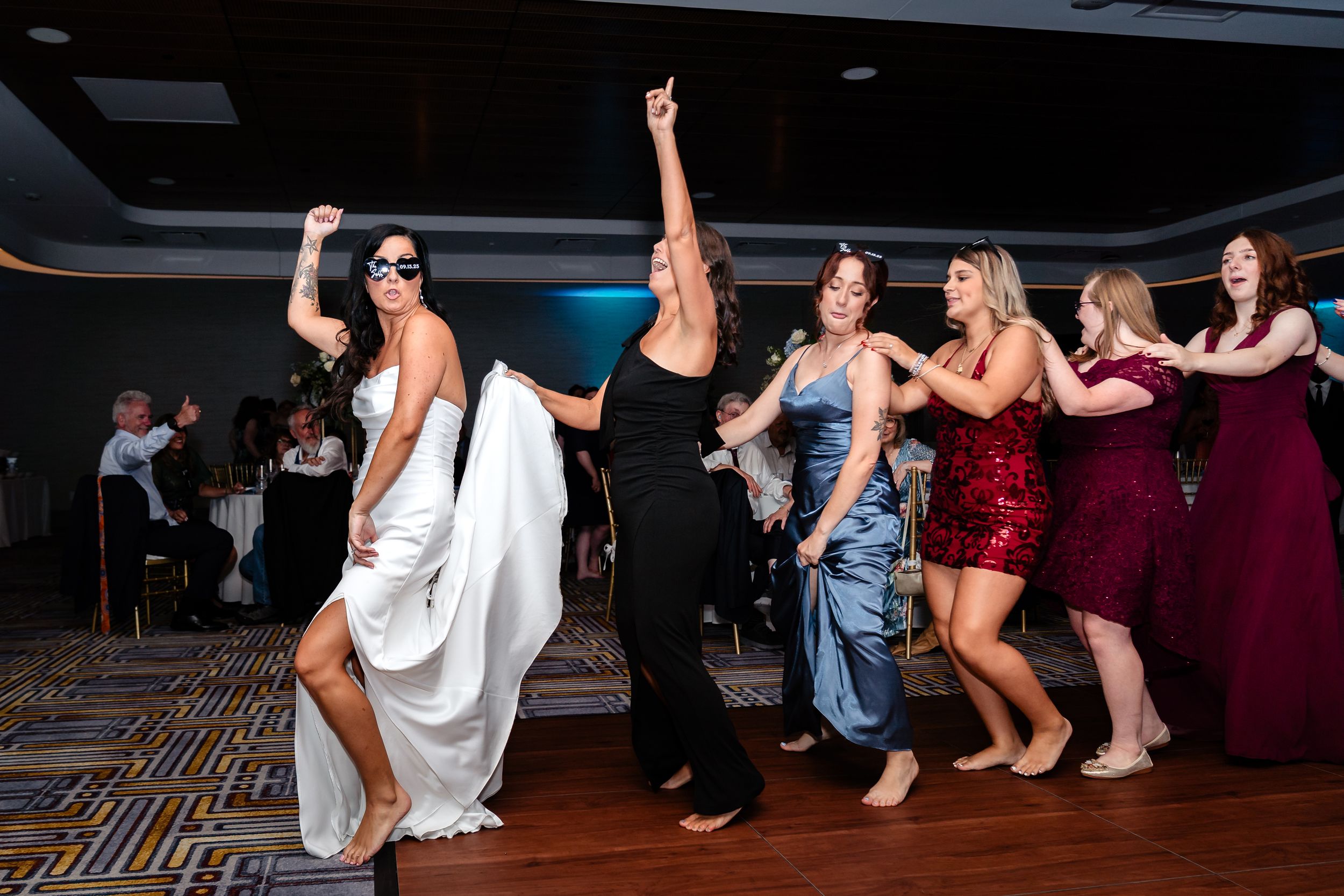 Wedding guests dance and celebrate together on a dark dance floor during an evening reception party.