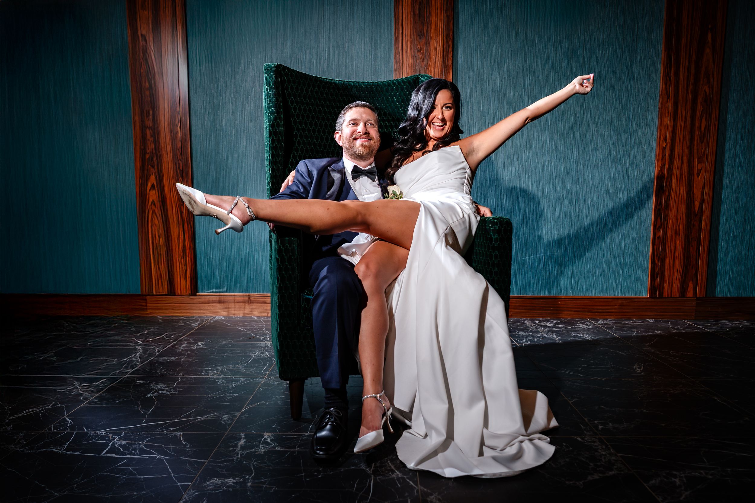 Wedding couple shares a romantic dance moment in a dimly lit room with dramatic lighting and wooden accents.