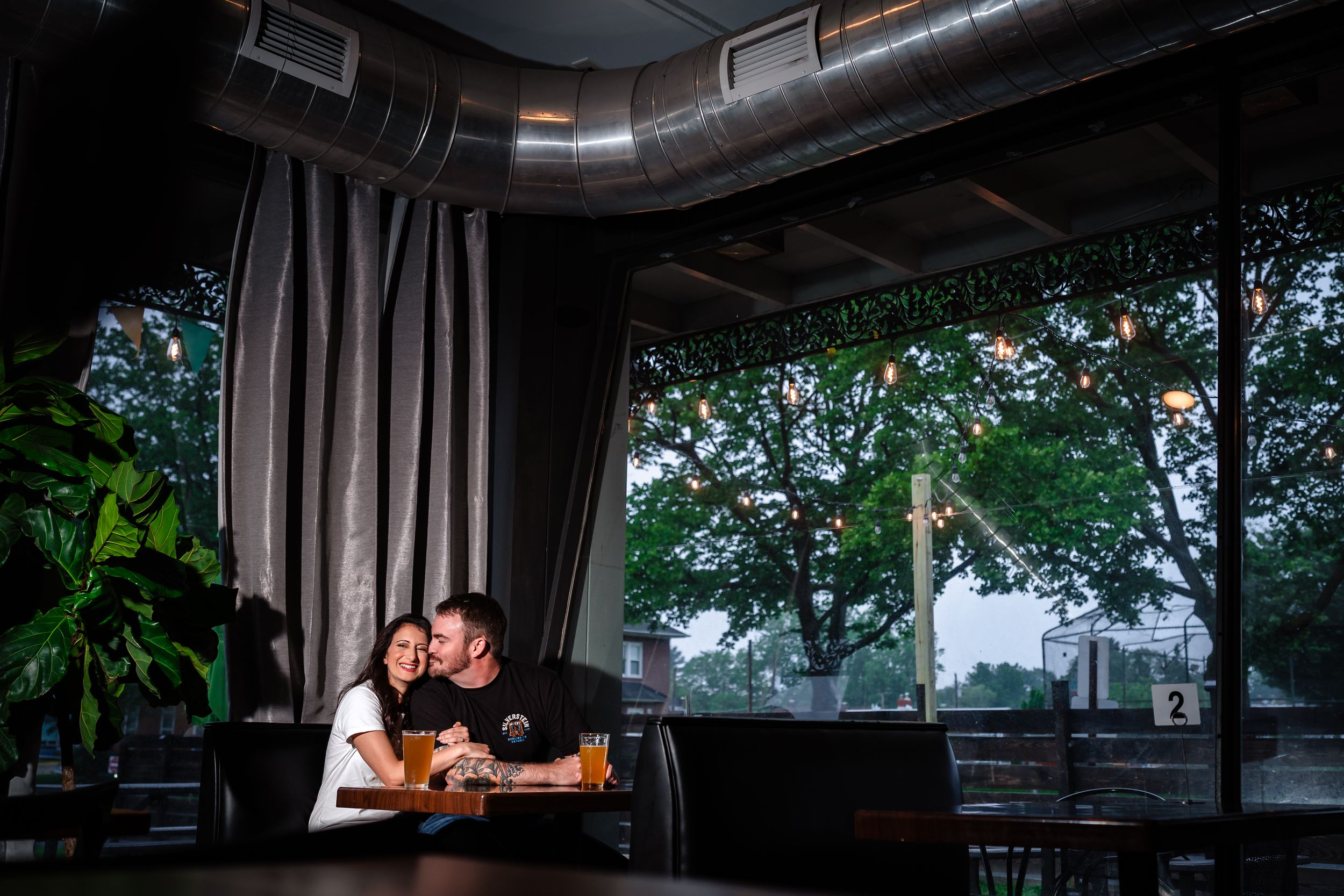 A dark and moody wedding photo session in an industrial venue with exposed ductwork and large windows.
