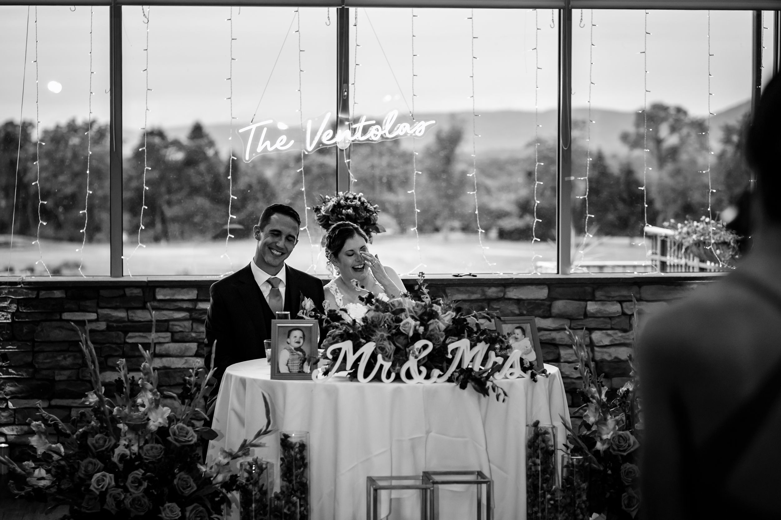 Wedding ceremony setup with white chairs and floral arrangements against a scenic outdoor backdrop.