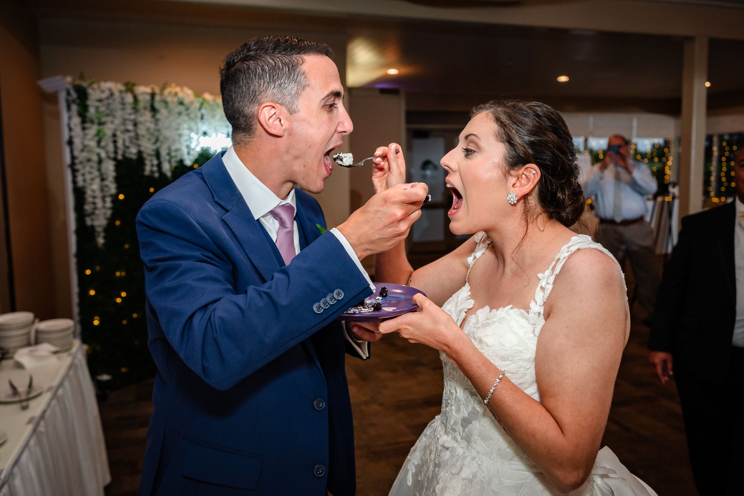 Newlyweds sharing cake during their wedding reception celebration.