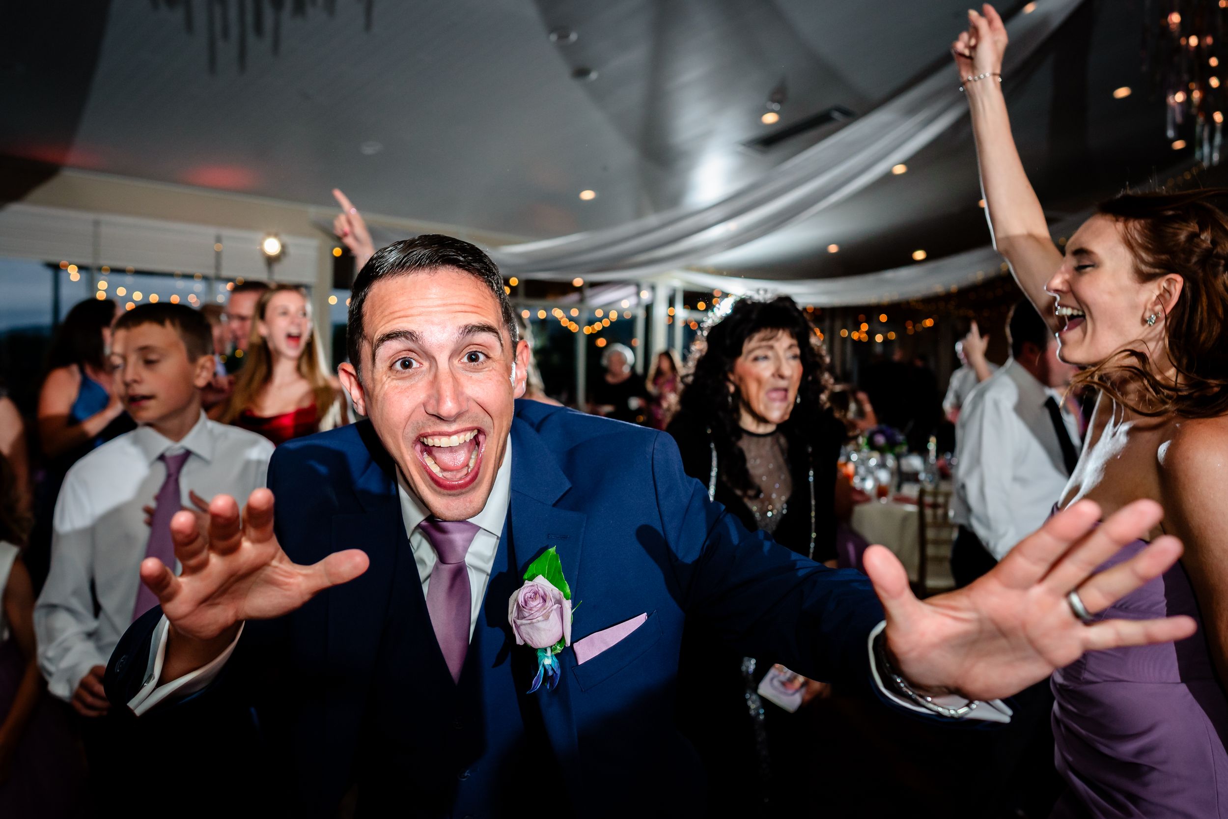 Wedding reception guests dancing and celebrating on a crowded dance floor under party lights.