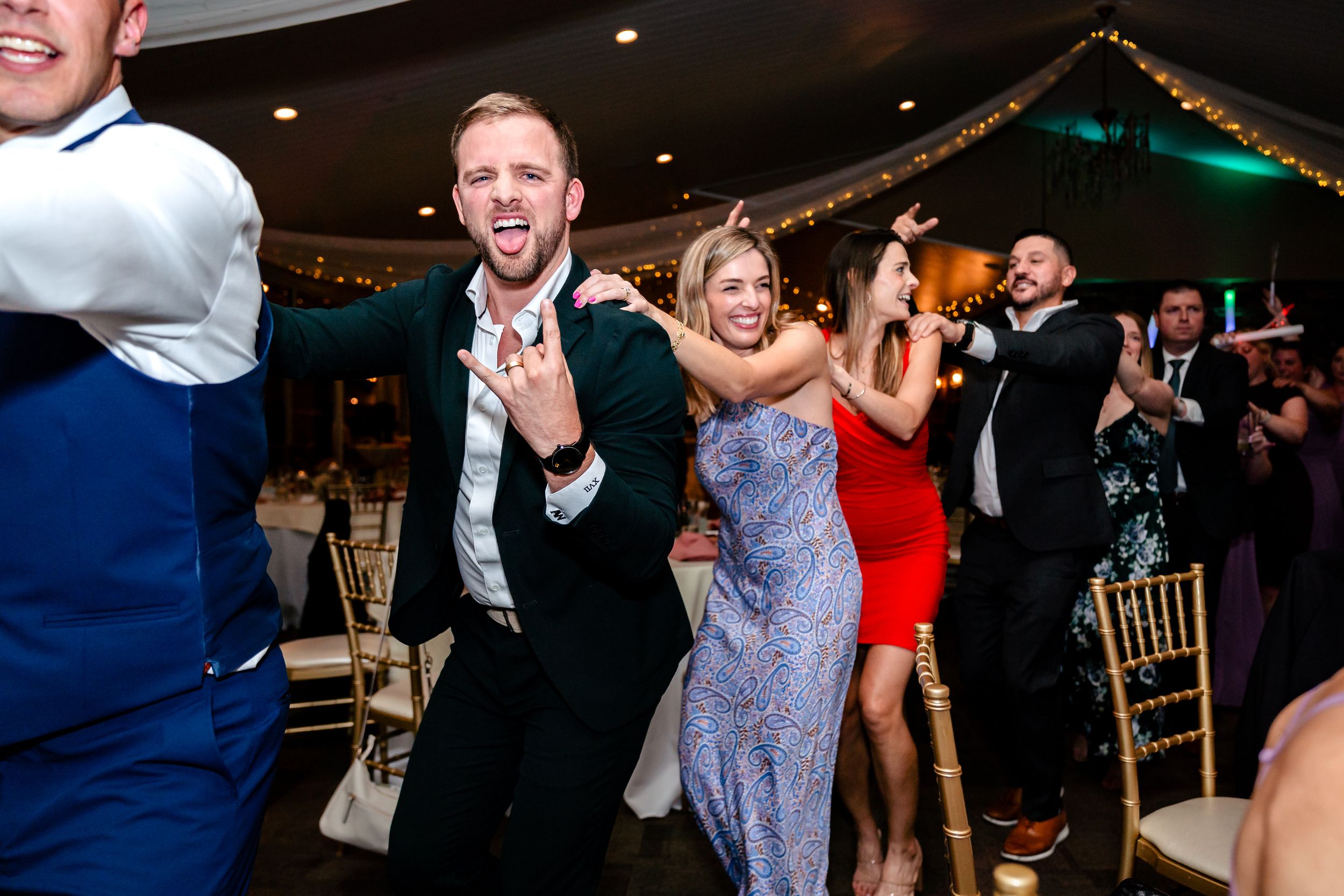 Lively dance floor scene with wedding guests celebrating and dancing in formal attire.
