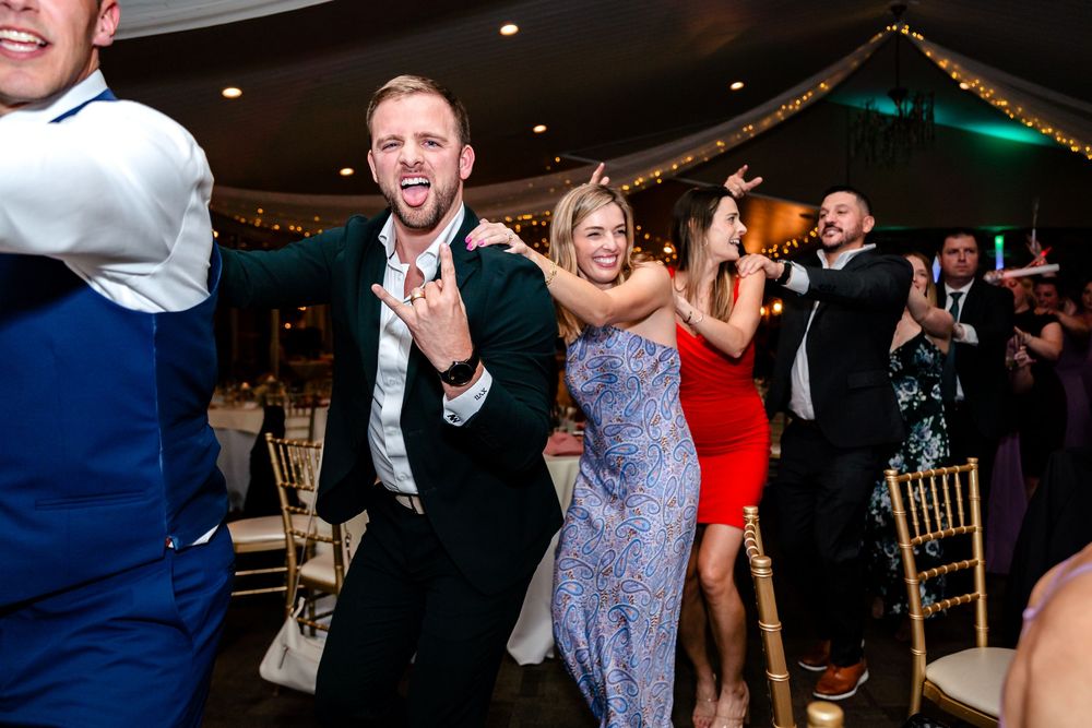 Lively dance floor scene with wedding guests celebrating and dancing in formal attire.