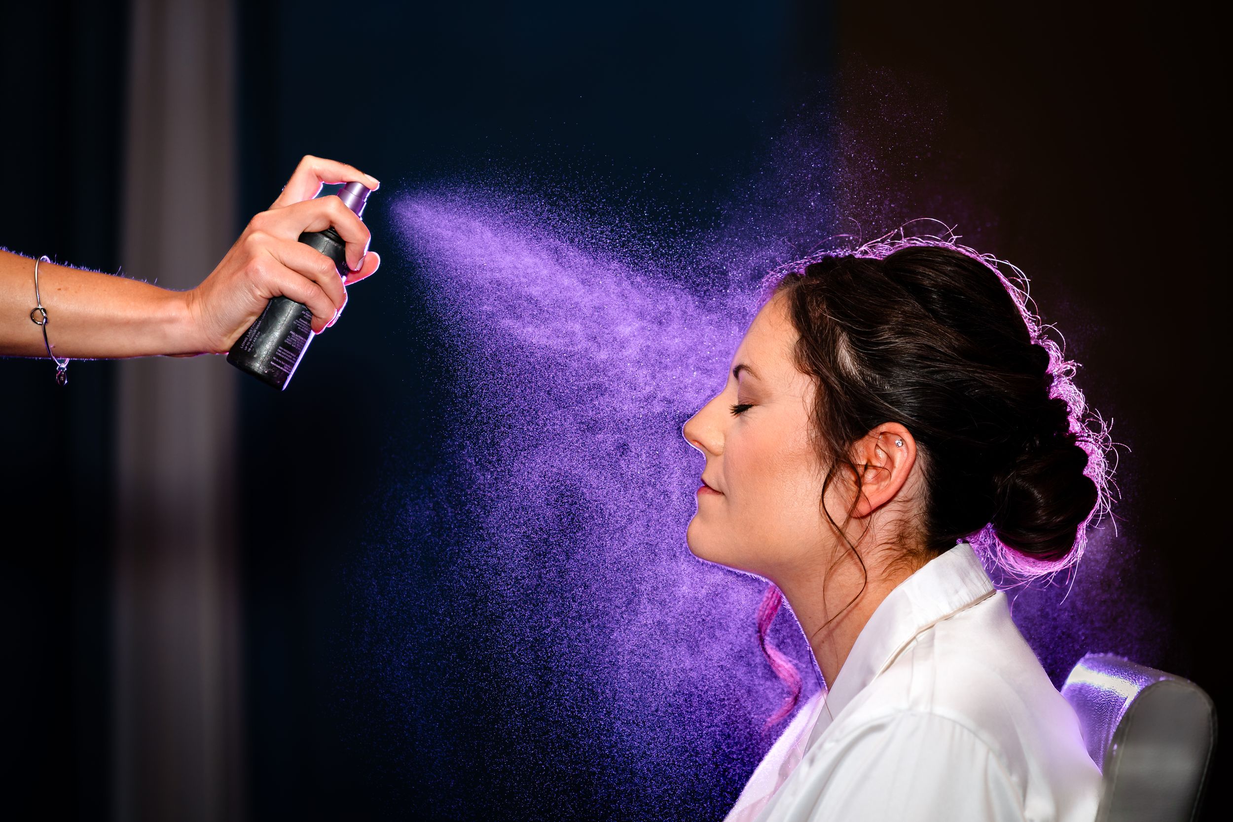 A sequence of photos showing purple hairspray being applied in a dramatic lighting setup at a wedding event.