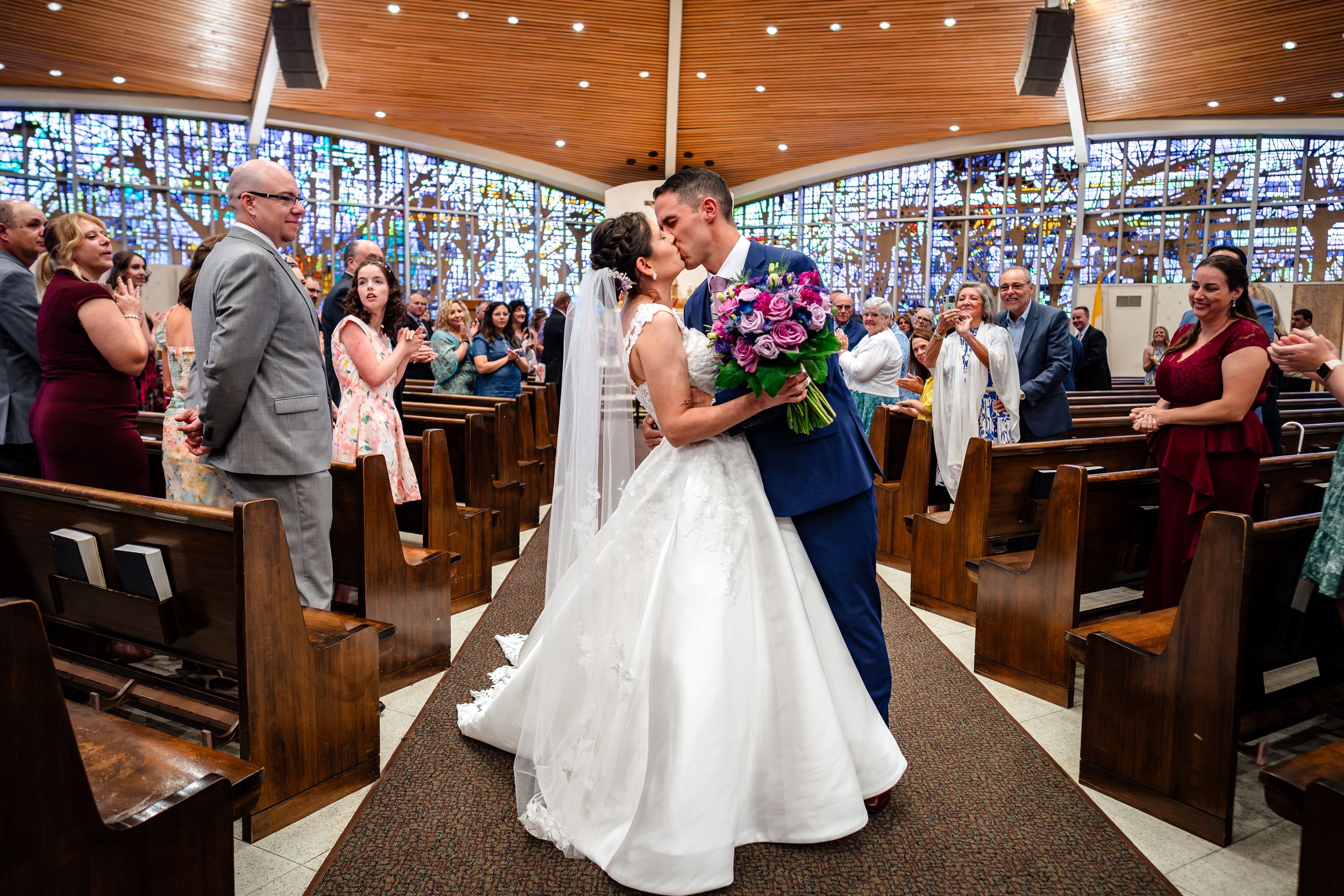 A wedding ceremony in a church with wooden pews and twinkling string lights overhead.