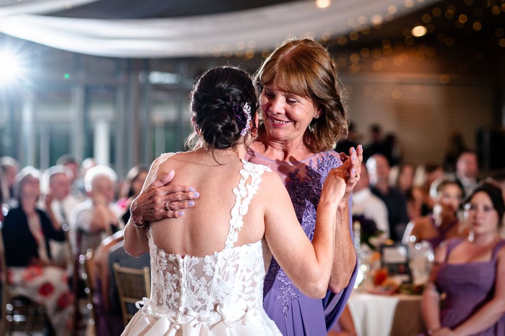 A couple shares a romantic dance at their wedding reception surrounded by guests on the dance floor.