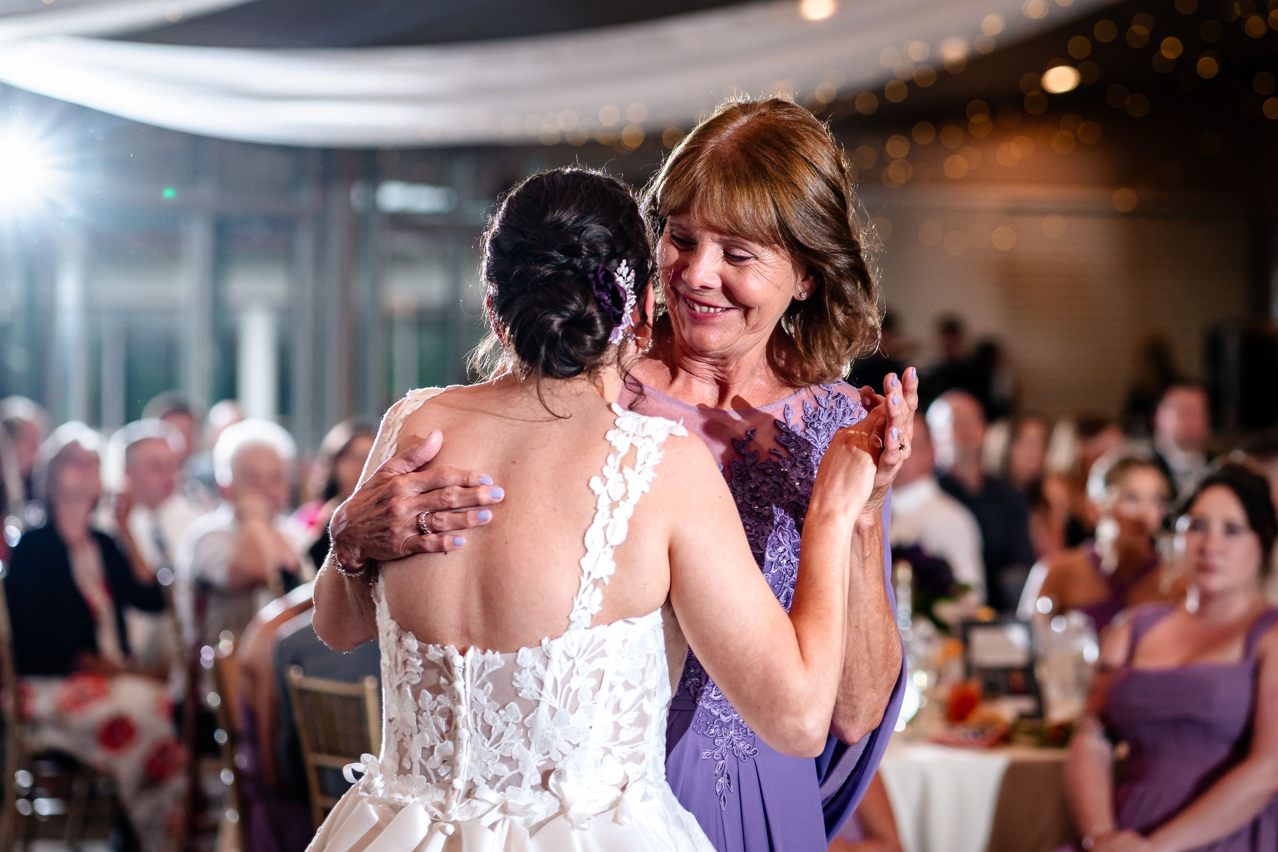 A couple shares a romantic dance at their wedding reception surrounded by guests on the dance floor.