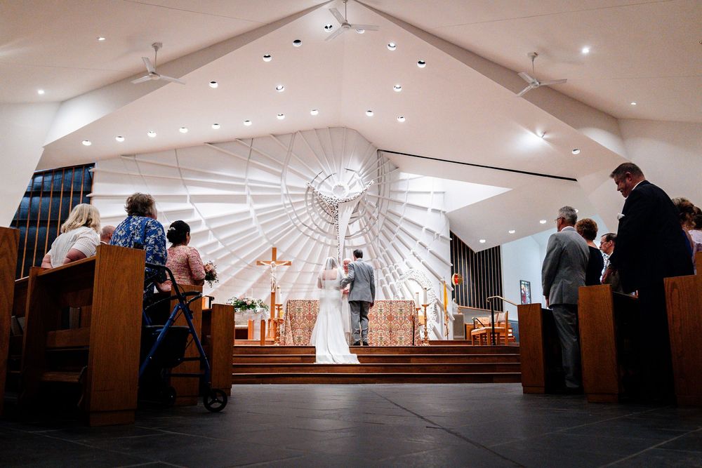 A panoramic view of an indoor event space with recessed lighting and people gathered in small groups.
