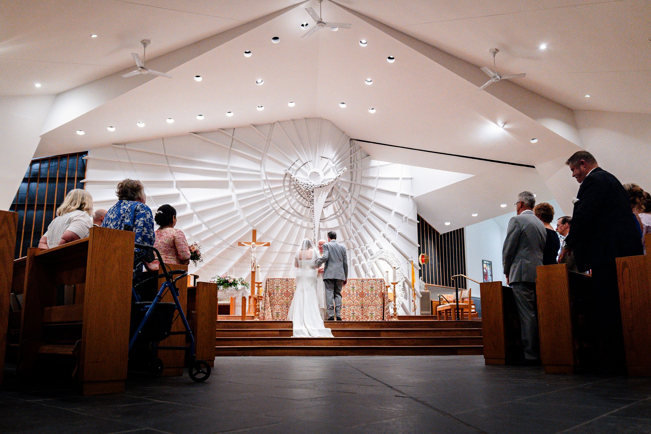 A panoramic view of an indoor event space with recessed lighting and people gathered in small groups.