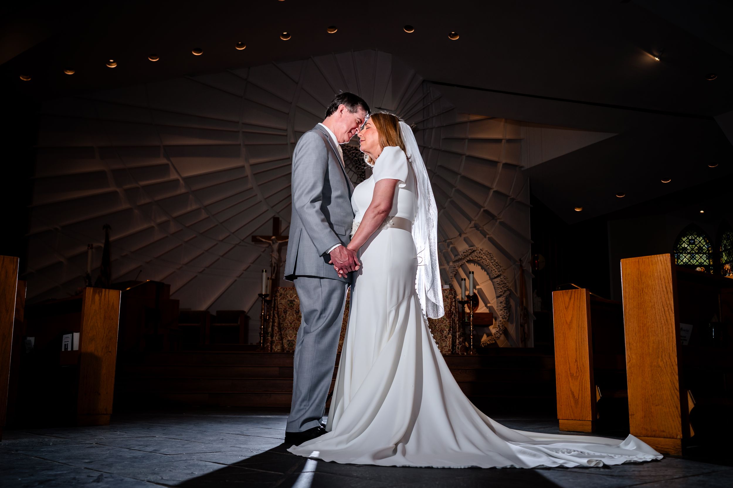 A romantic wedding couple shares an intimate dance together on a dimly lit wooden floor.