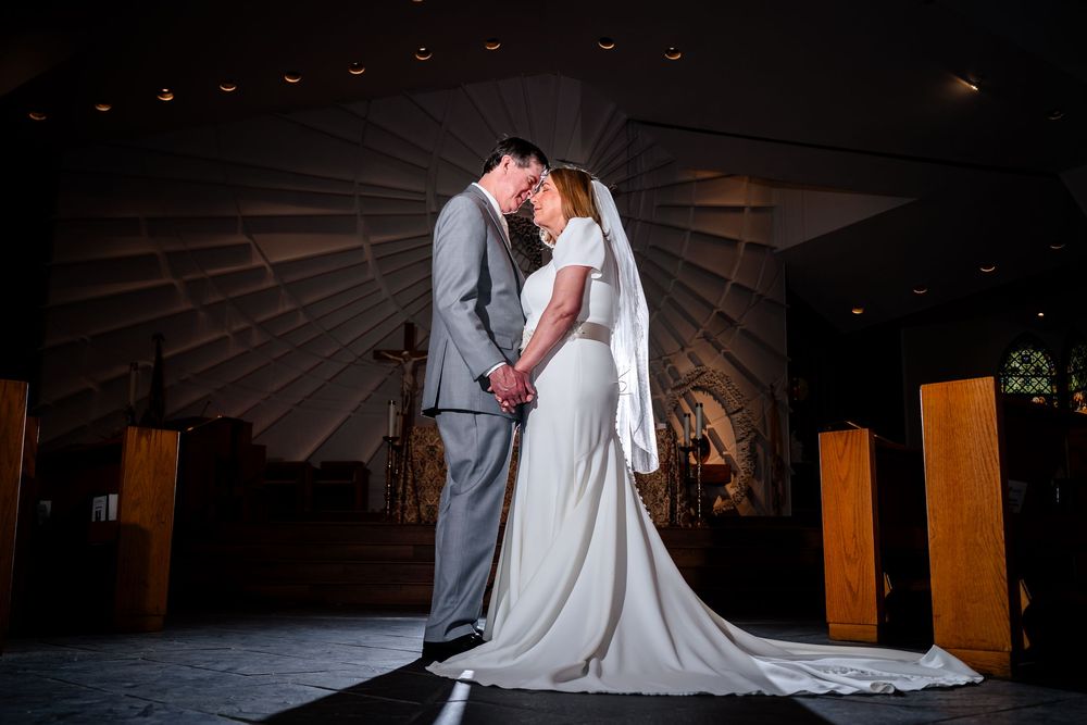 A romantic wedding couple shares an intimate dance together on a dimly lit wooden floor.