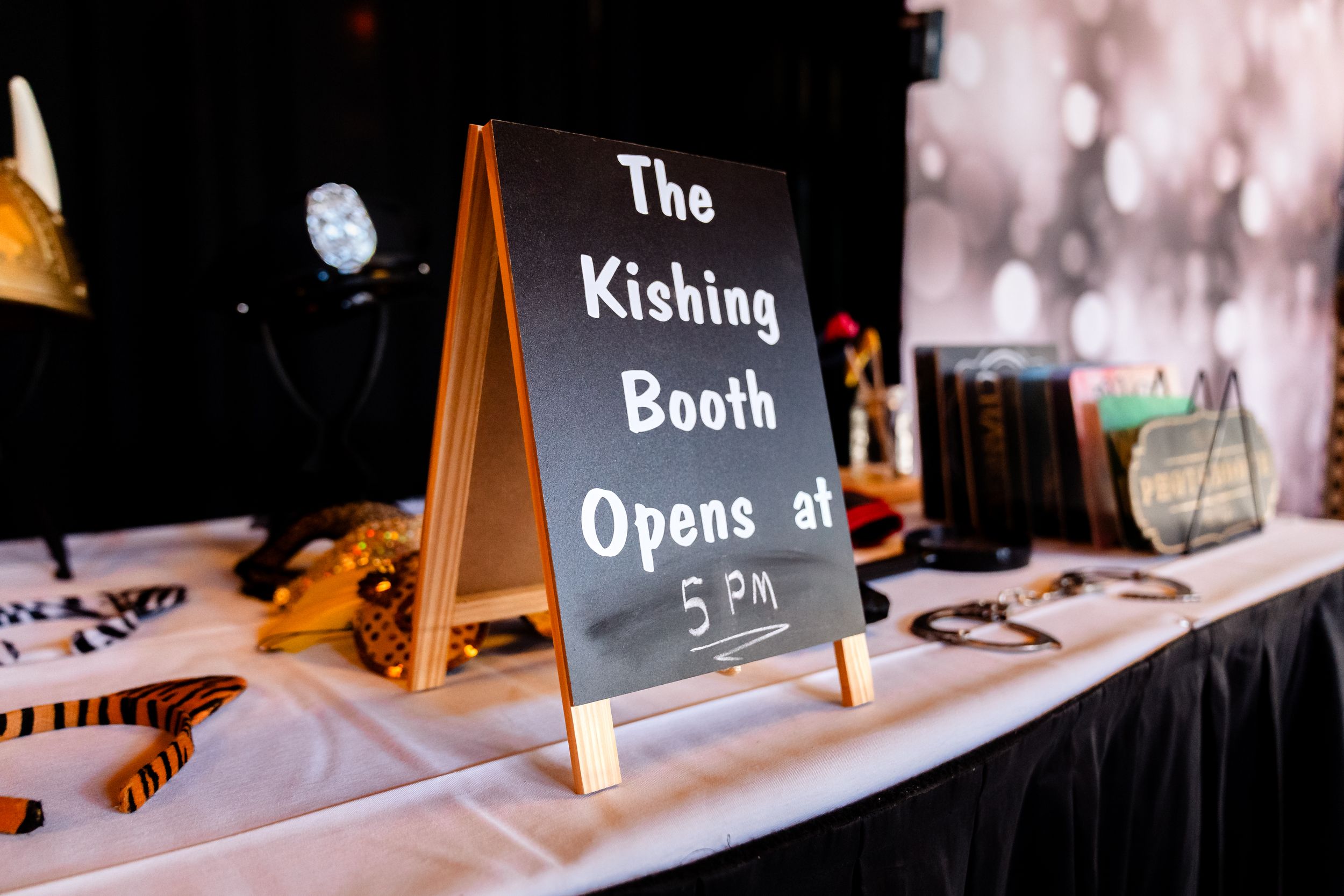 A row of small chalkboard signs and decorative displays set up on a white tablecloth for an event.