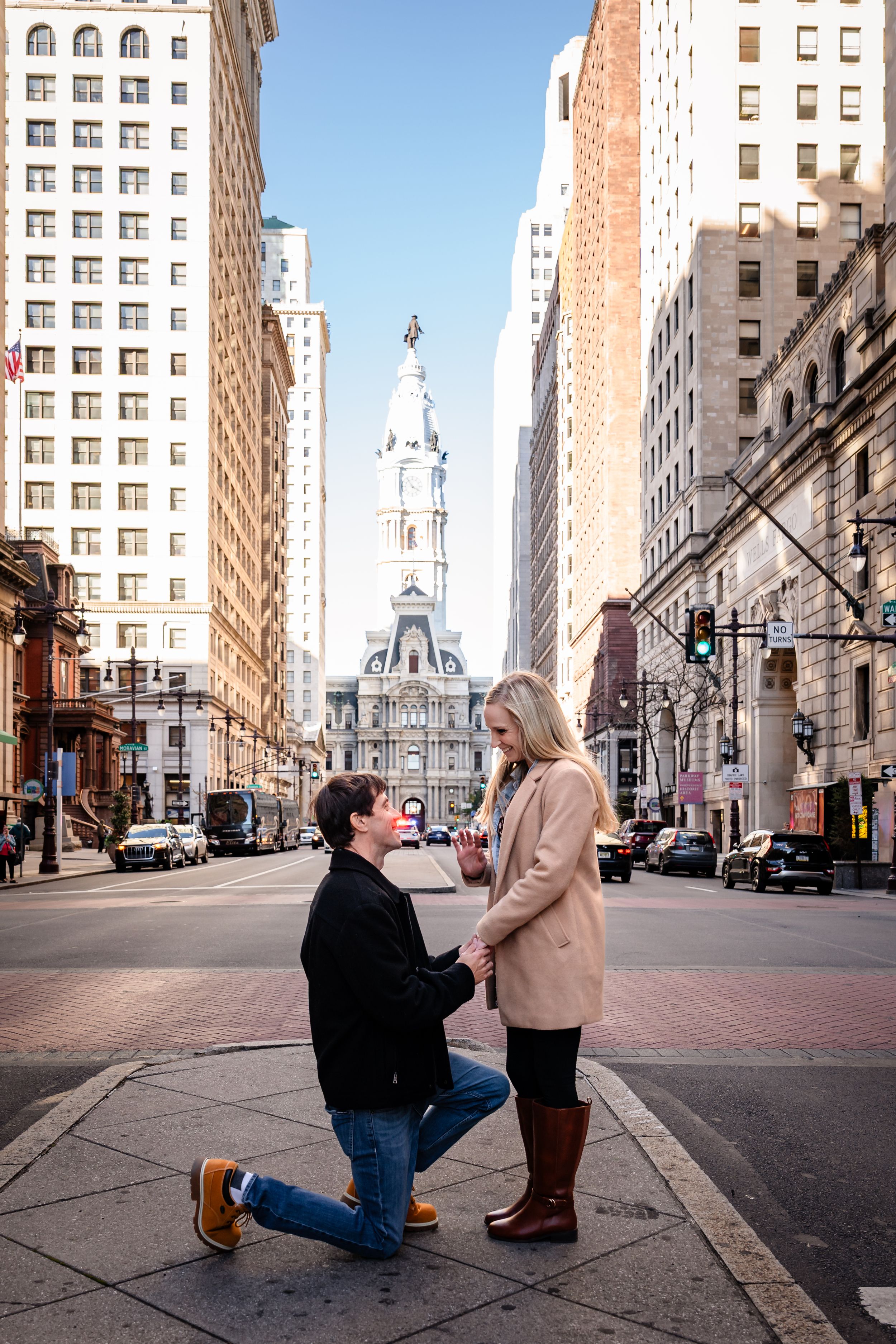 A romantic proposal scene unfolds on a city street corner with tall buildings in the background.
