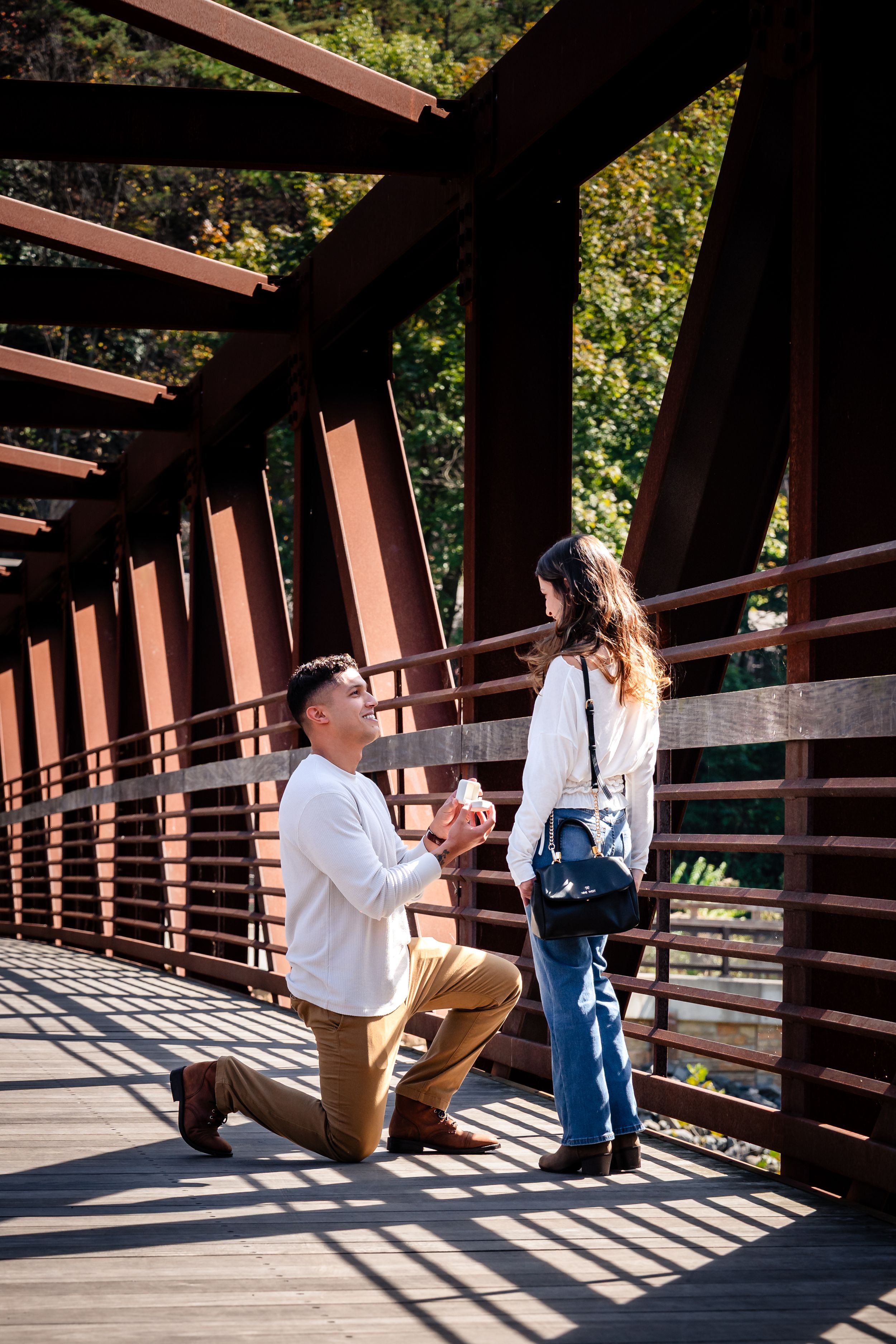 A romantic proposal sequence on a wooden bridge with sunlight streaming through the railings, creating dramatic shadows.
