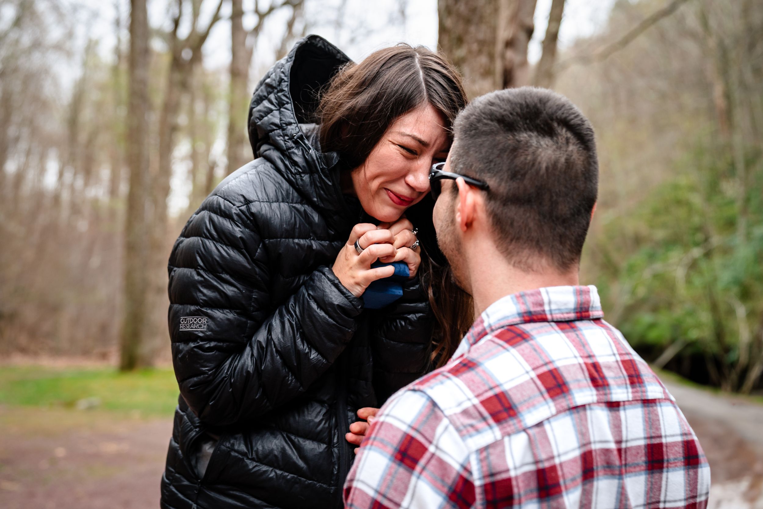 A couple embraces outdoors in a winter park setting while sharing a romantic moment together.