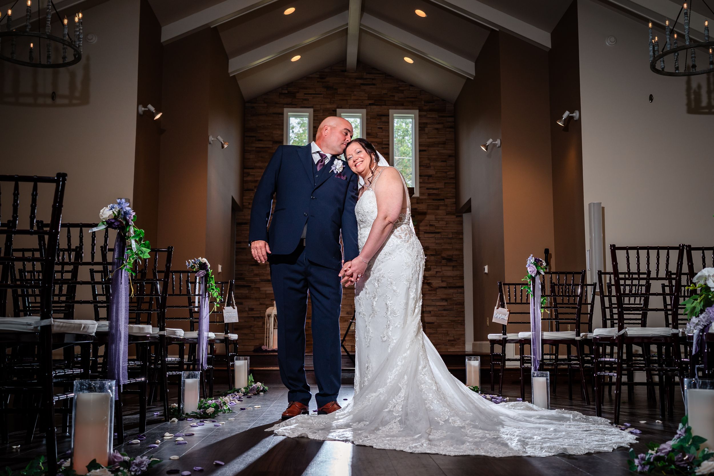 A romantic wedding couple poses together in an elegant indoor venue with dramatic lighting and architectural details.