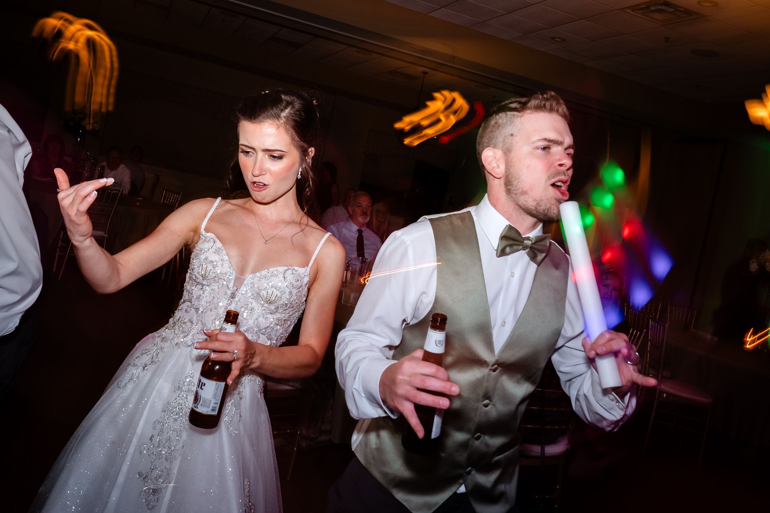 Wedding reception dance party with colorful lights and celebratory atmosphere in dark venue.