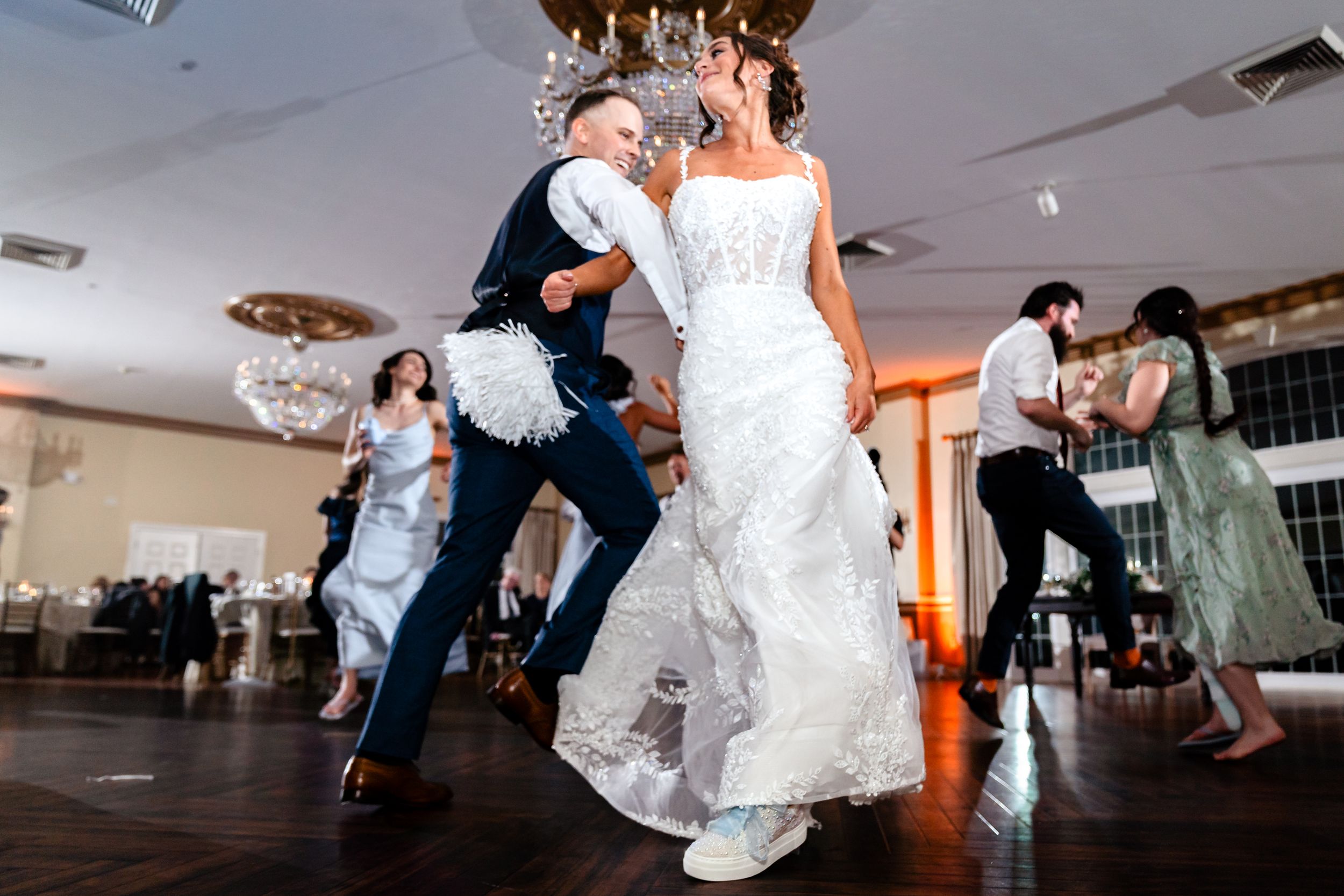 Couple dancing together at a wedding reception with the bride's white dress flowing gracefully during their spin.