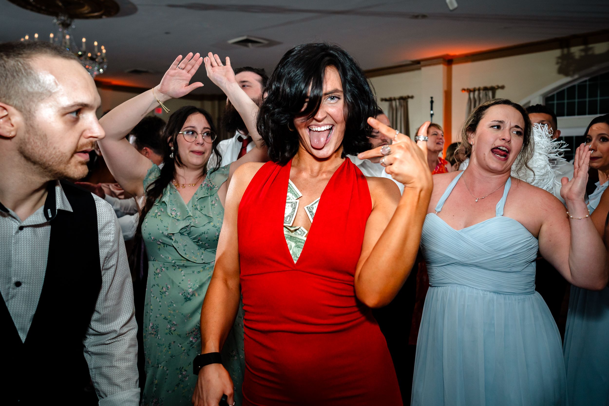 Wedding guests dancing and celebrating at a reception party with people in red and blue dresses.