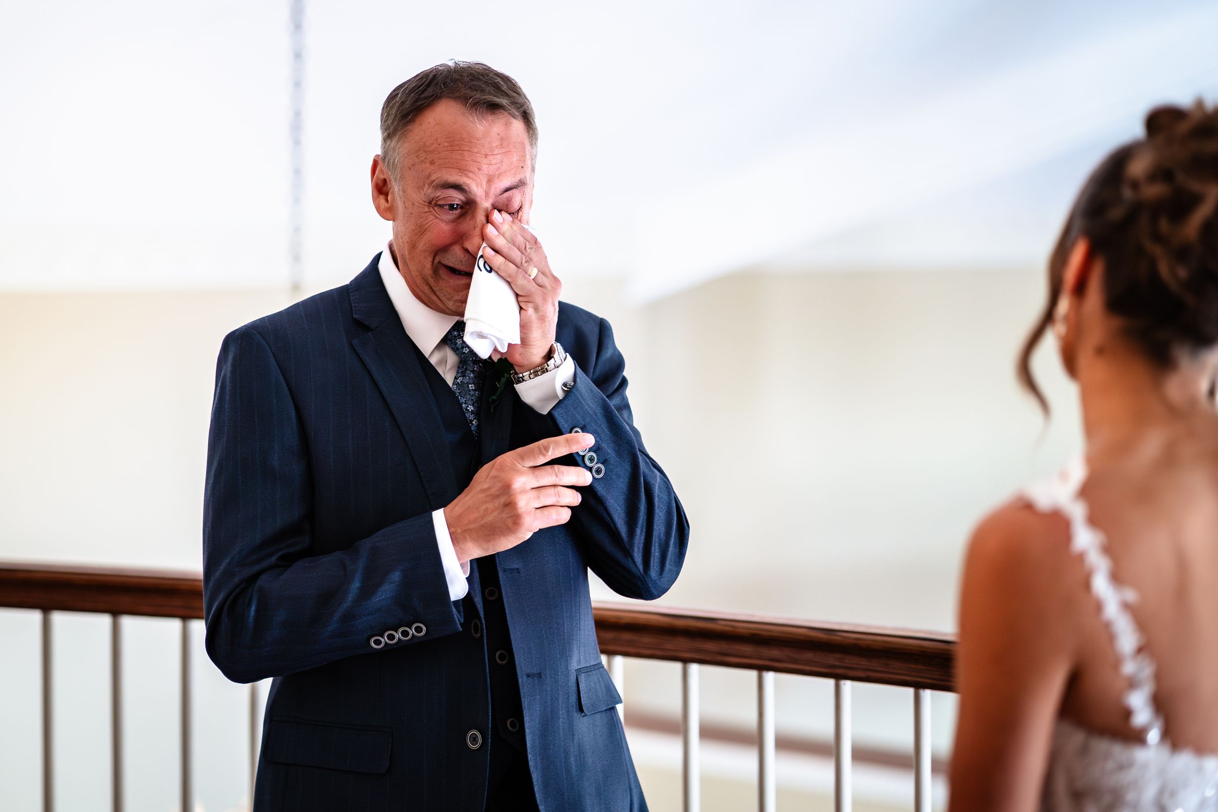A touching first look wedding moment between a couple with the groom wiping away tears of joy.