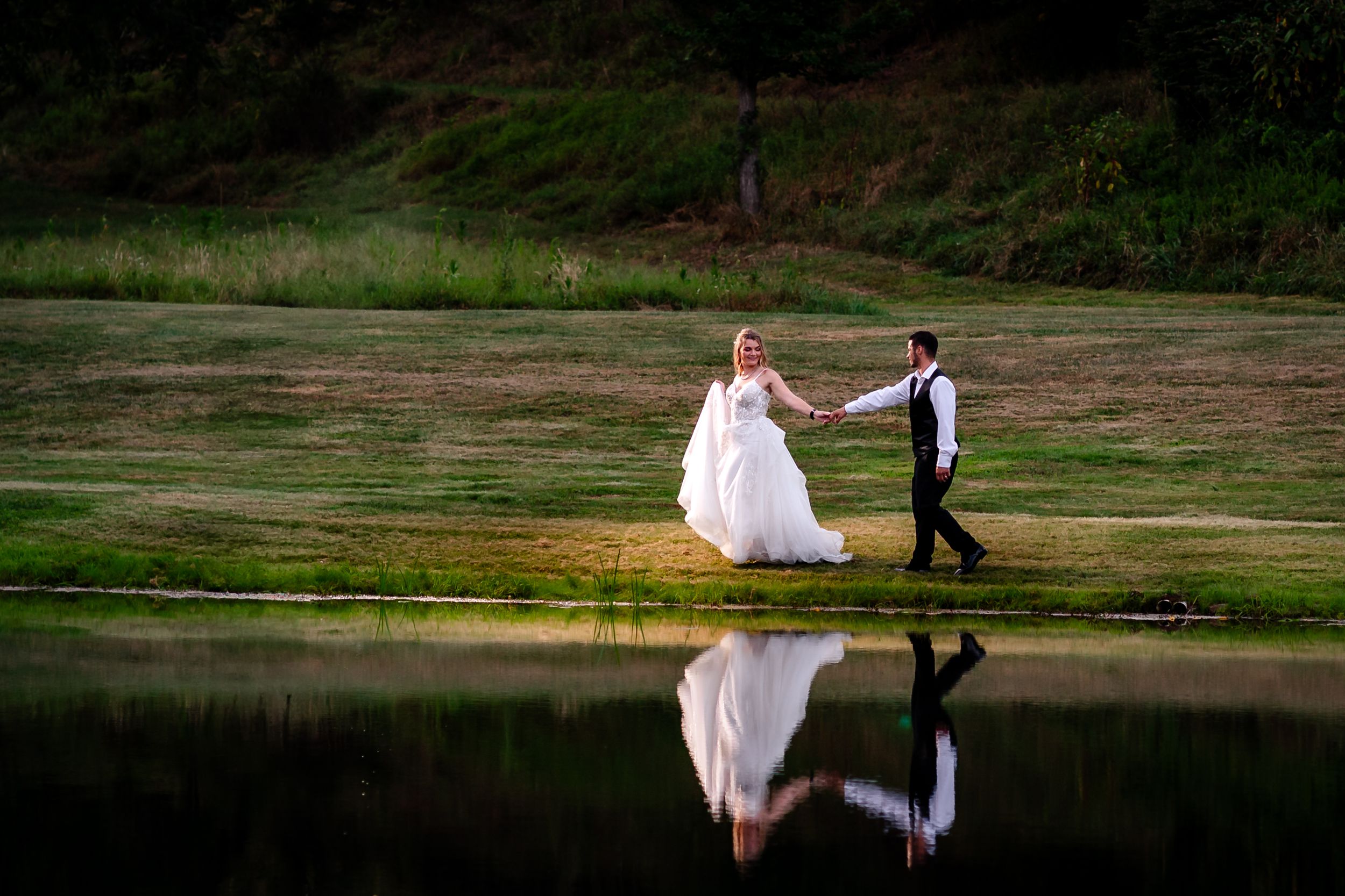 A couple in wedding attire poses for romantic photos on a scenic golf course fairway at sunset.