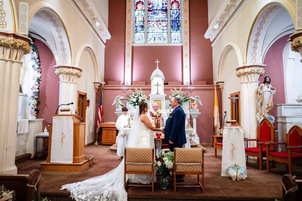 A panoramic view of a church interior with stained glass windows, ornate columns, and white arches in traditional design.