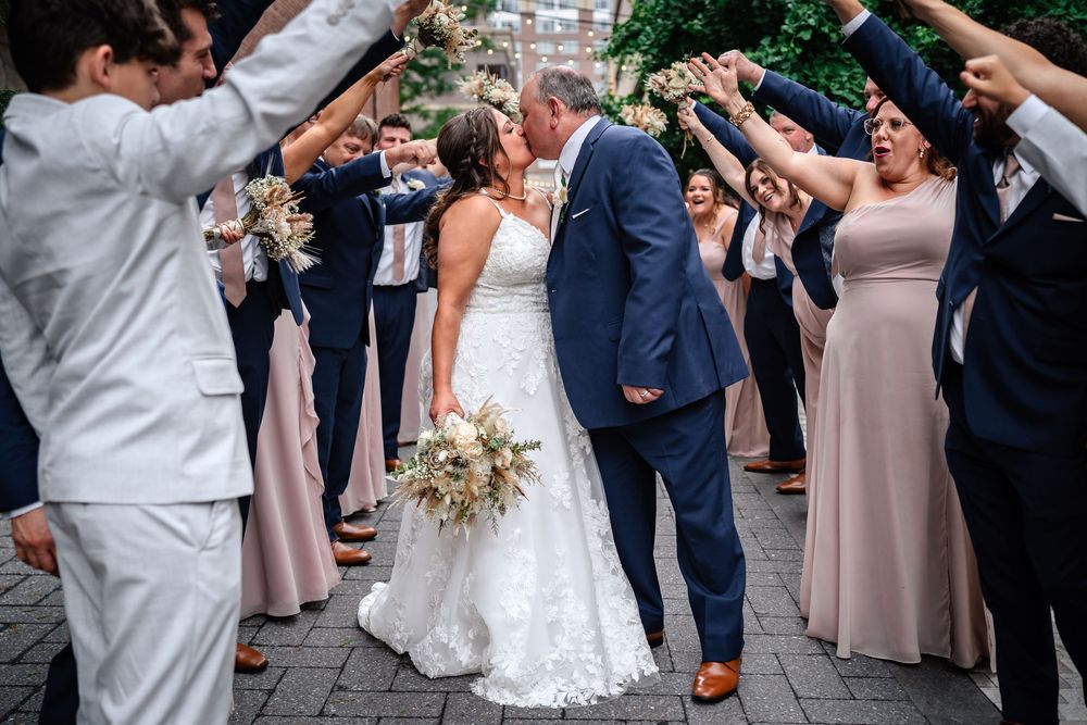 Wedding couple and guests celebrate joyfully on the dance floor during a reception.