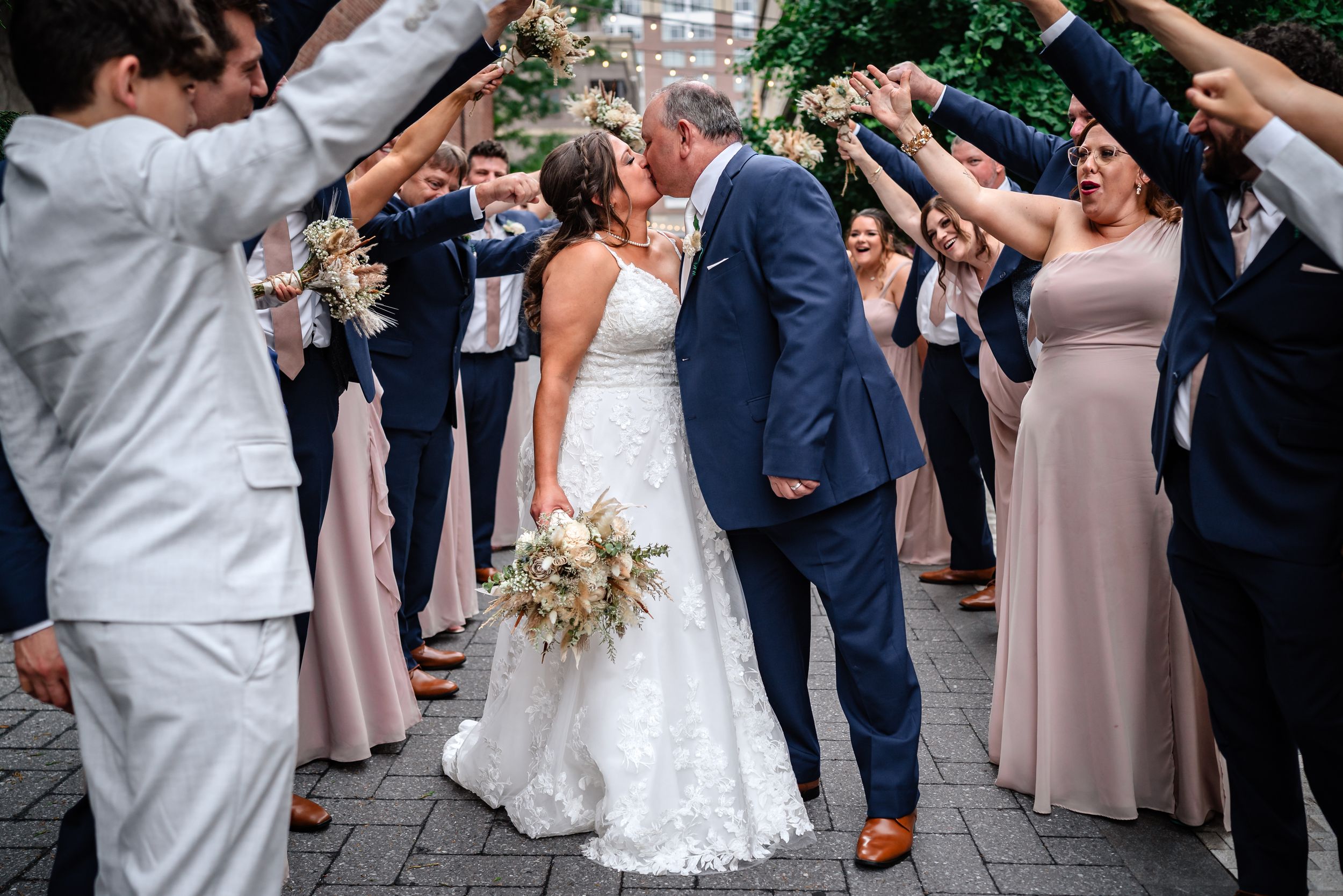 Wedding couple and guests celebrate joyfully on the dance floor during a reception.
