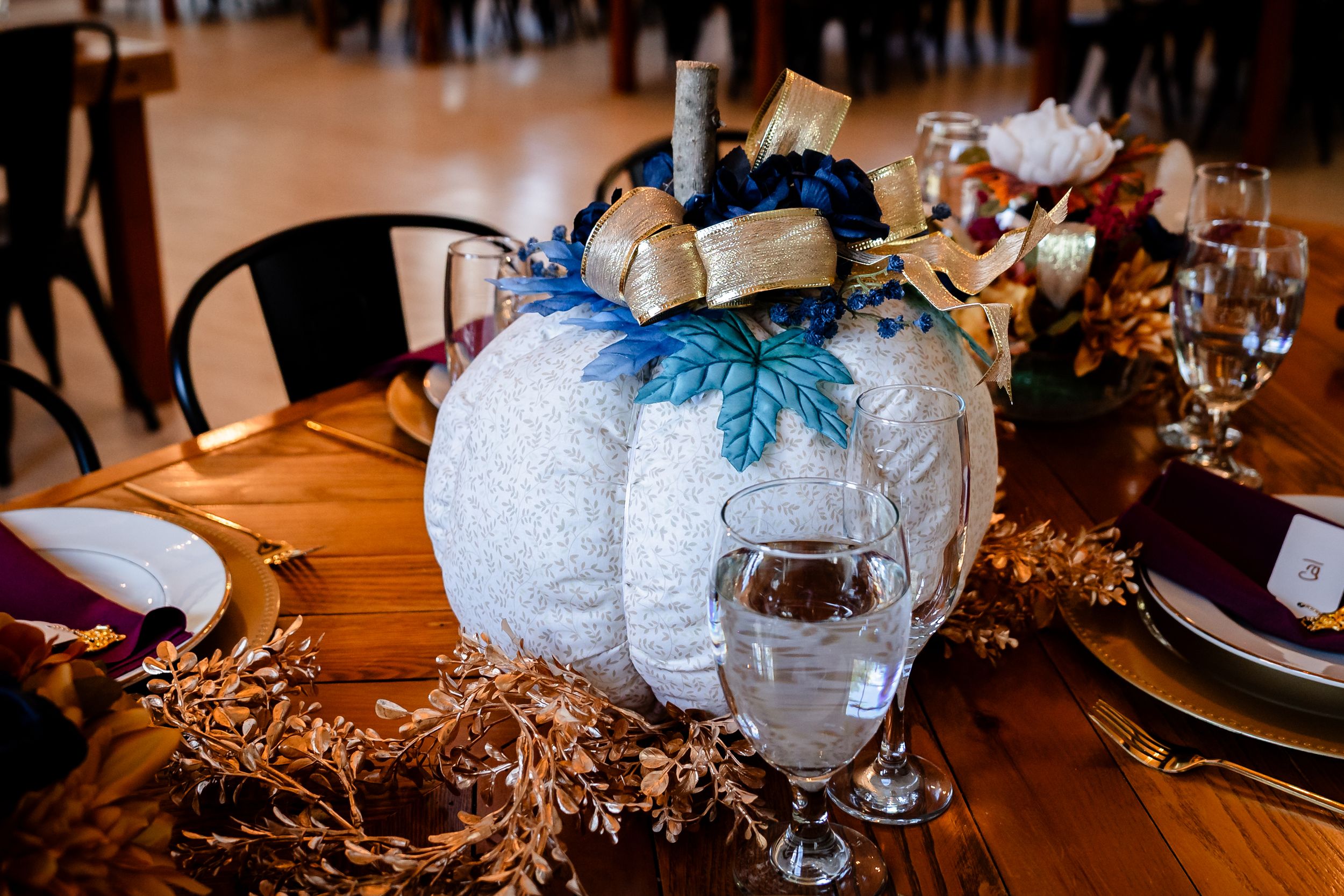 Elegant table settings with white pumpkin centerpieces and glowing candles create a romantic autumn atmosphere.