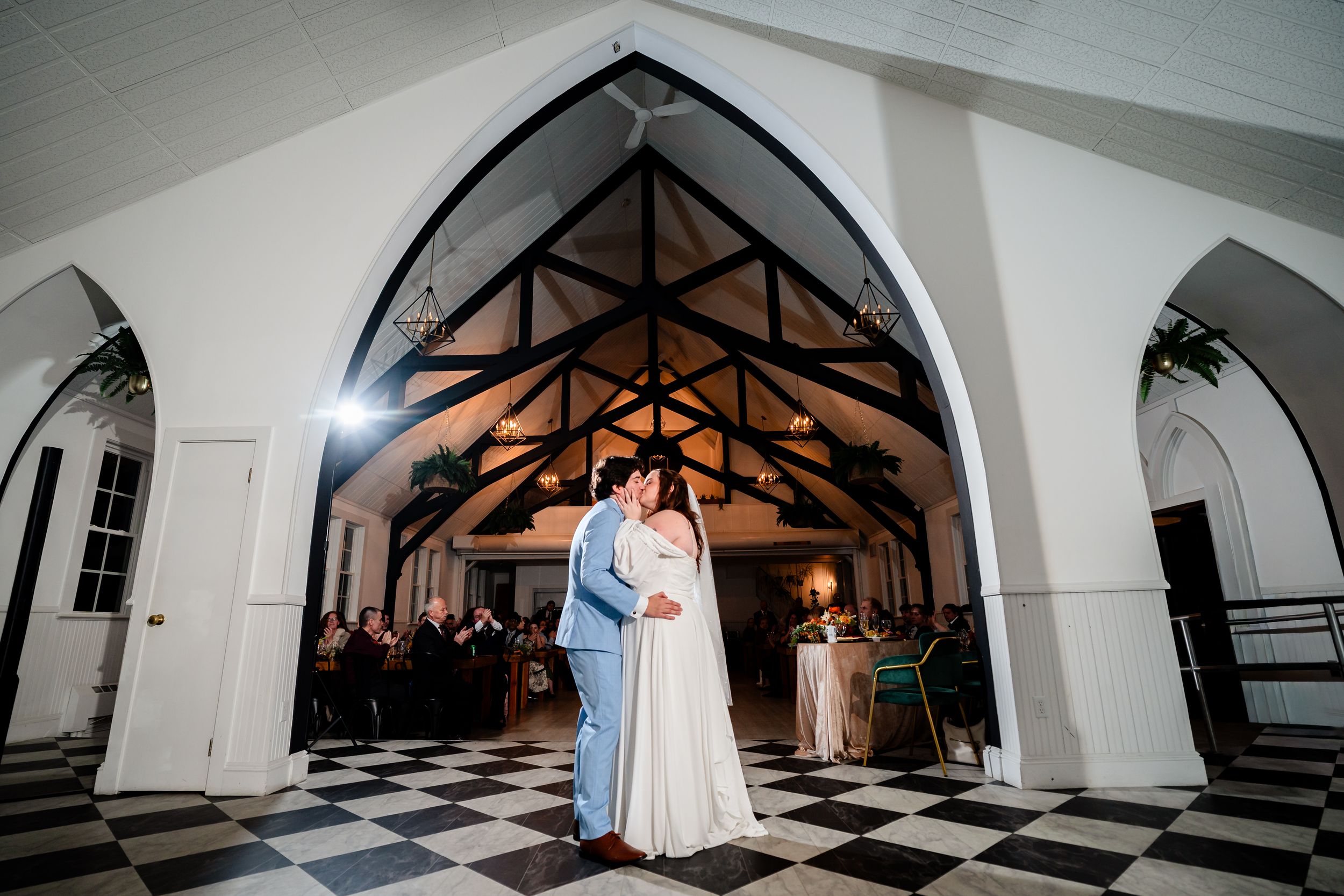 A series of dramatic black and white wedding photos showing a couple dancing in a grand checkered-floor ballroom.