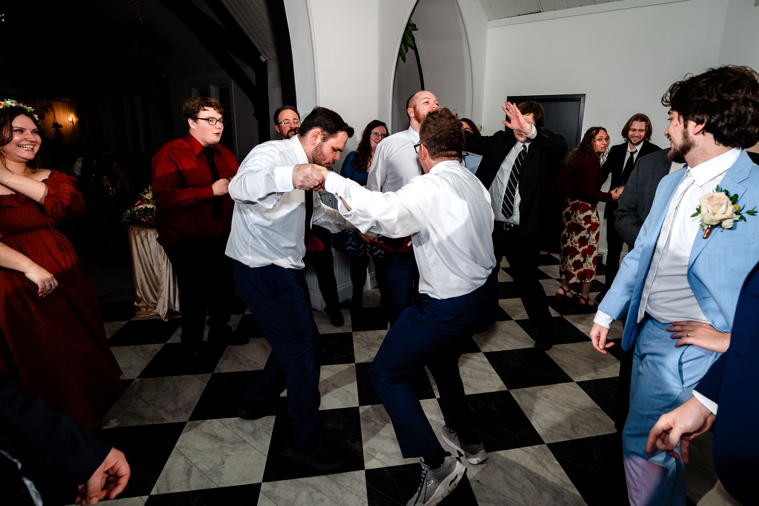 People dancing together on a black and white checkered floor at a social gathering or party.
