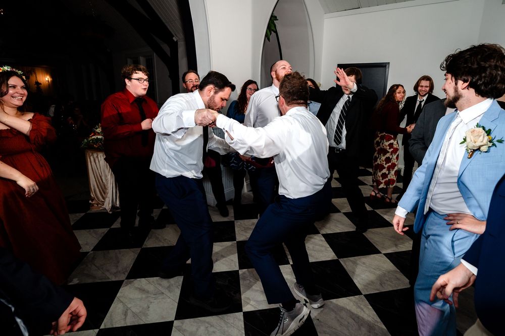 People dancing together on a black and white checkered floor at a social gathering or party.