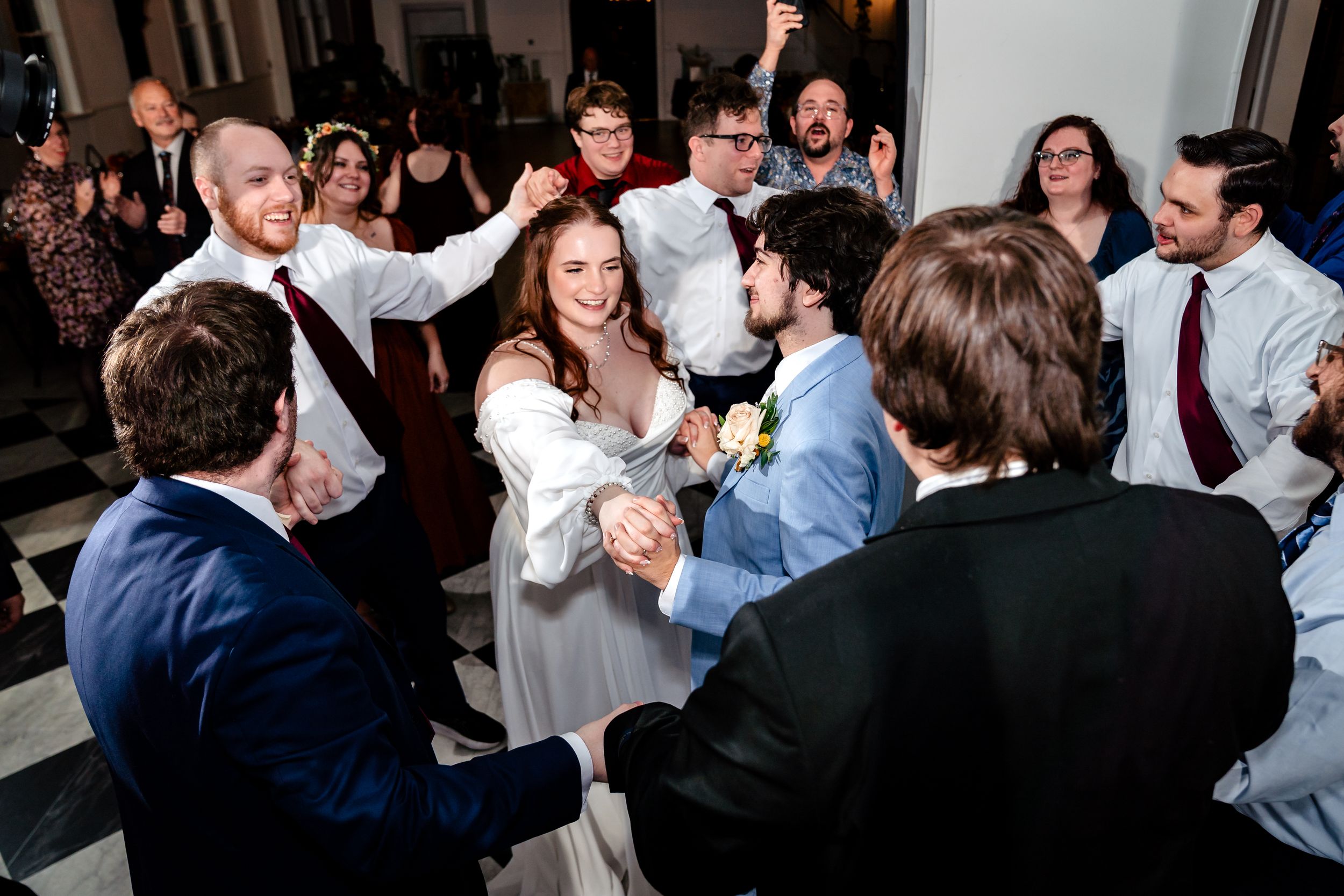 Wedding guests dancing and celebrating together on a crowded dance floor during an evening reception.