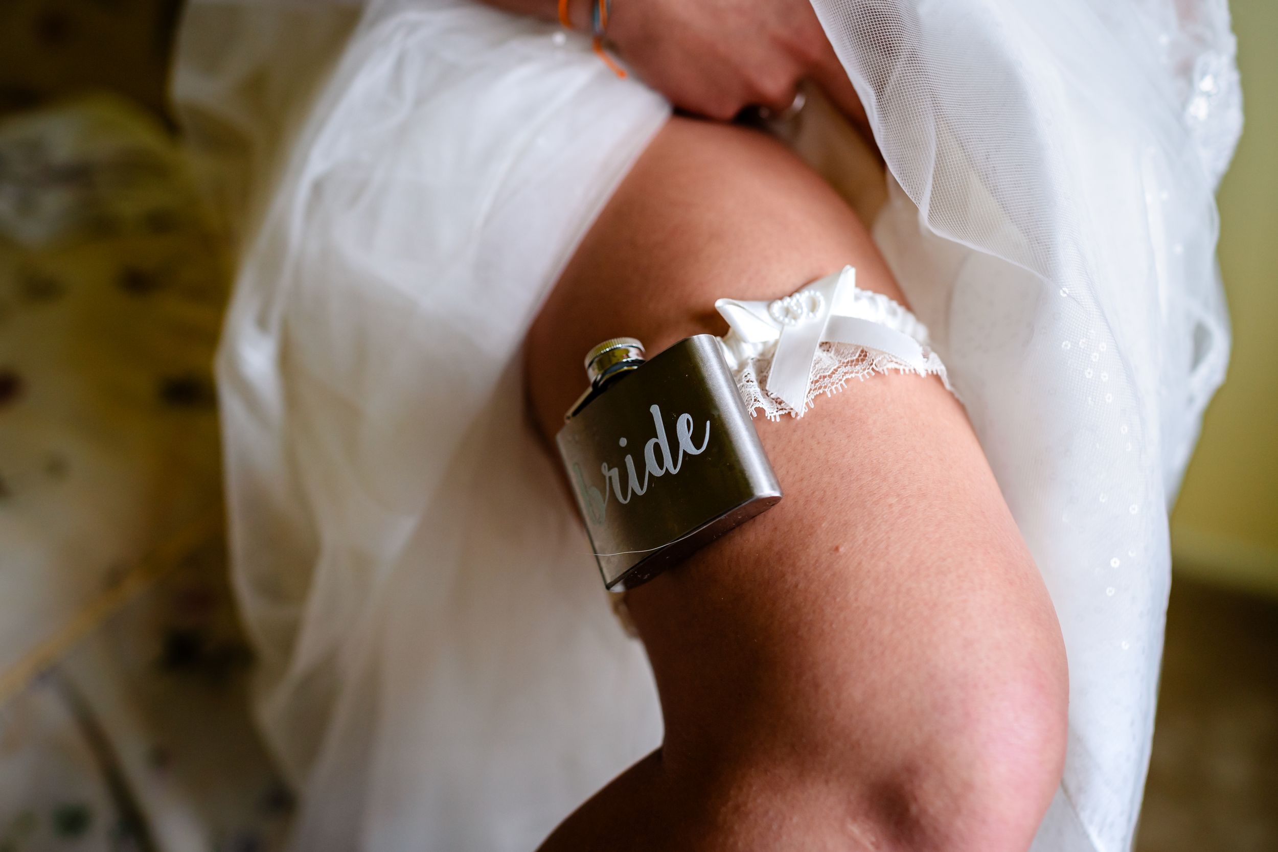 Close-up shot of hands wearing wedding rings with the words bride and groom engraved on them.