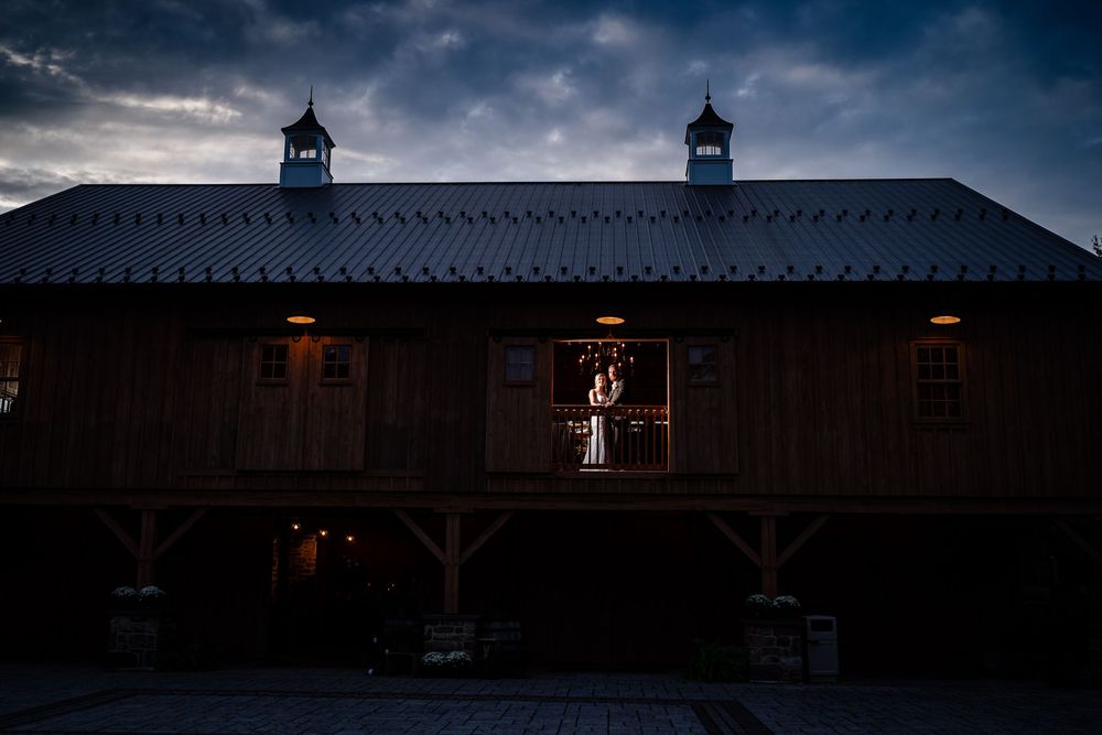 Dark moody wedding venue exterior with dramatic cloudy sky and silhouetted architectural details.