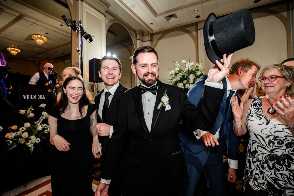 Wedding guests dancing and celebrating on dimly lit dance floor at reception.