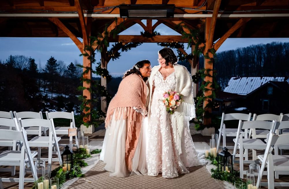 Wedding ceremony venue decorated with wooden beams and white chairs in an outdoor rustic setting.