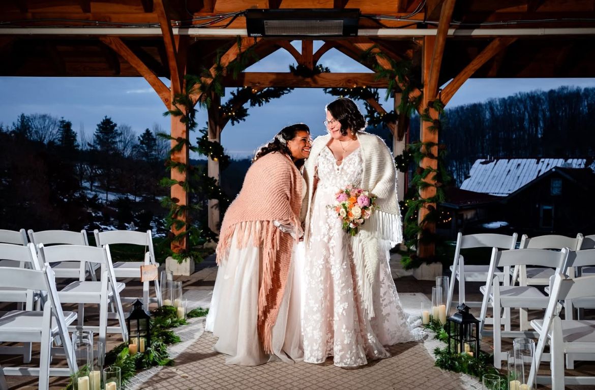 Wedding ceremony venue decorated with wooden beams and white chairs in an outdoor rustic setting.