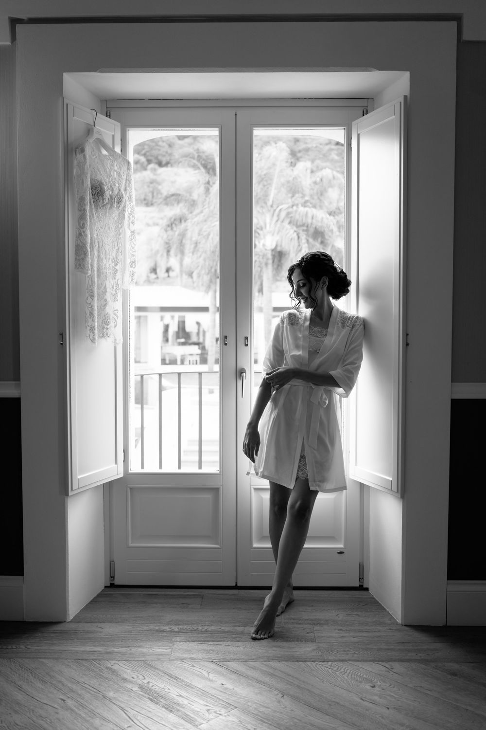 Black and white photograph of a silhouetted figure standing in a doorway with French doors and natural light streaming in.