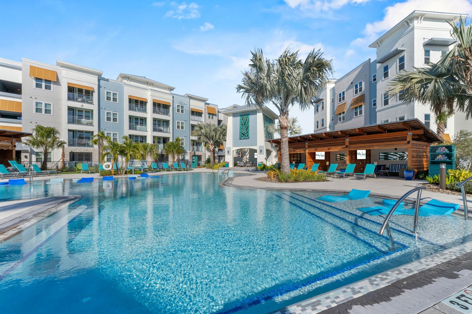 Modern apartment complex features a luxurious resort-style swimming pool with crystal clear water and palm trees.