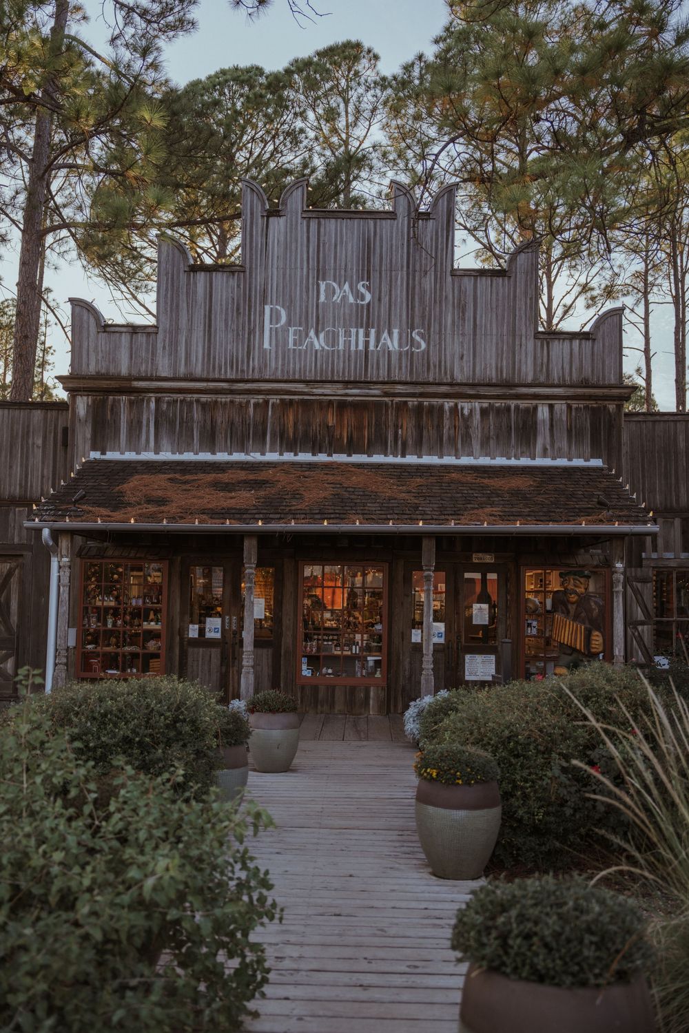 Rustic wooden storefront with 'Peachtrees' sign and outdoor deck surrounded by greenery.