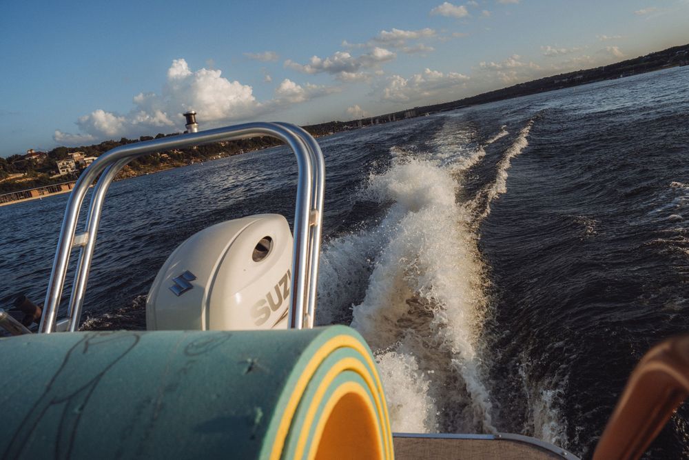 A Suzuki outboard motor powers a speedboat across choppy ocean waters, leaving a white wake trail behind.