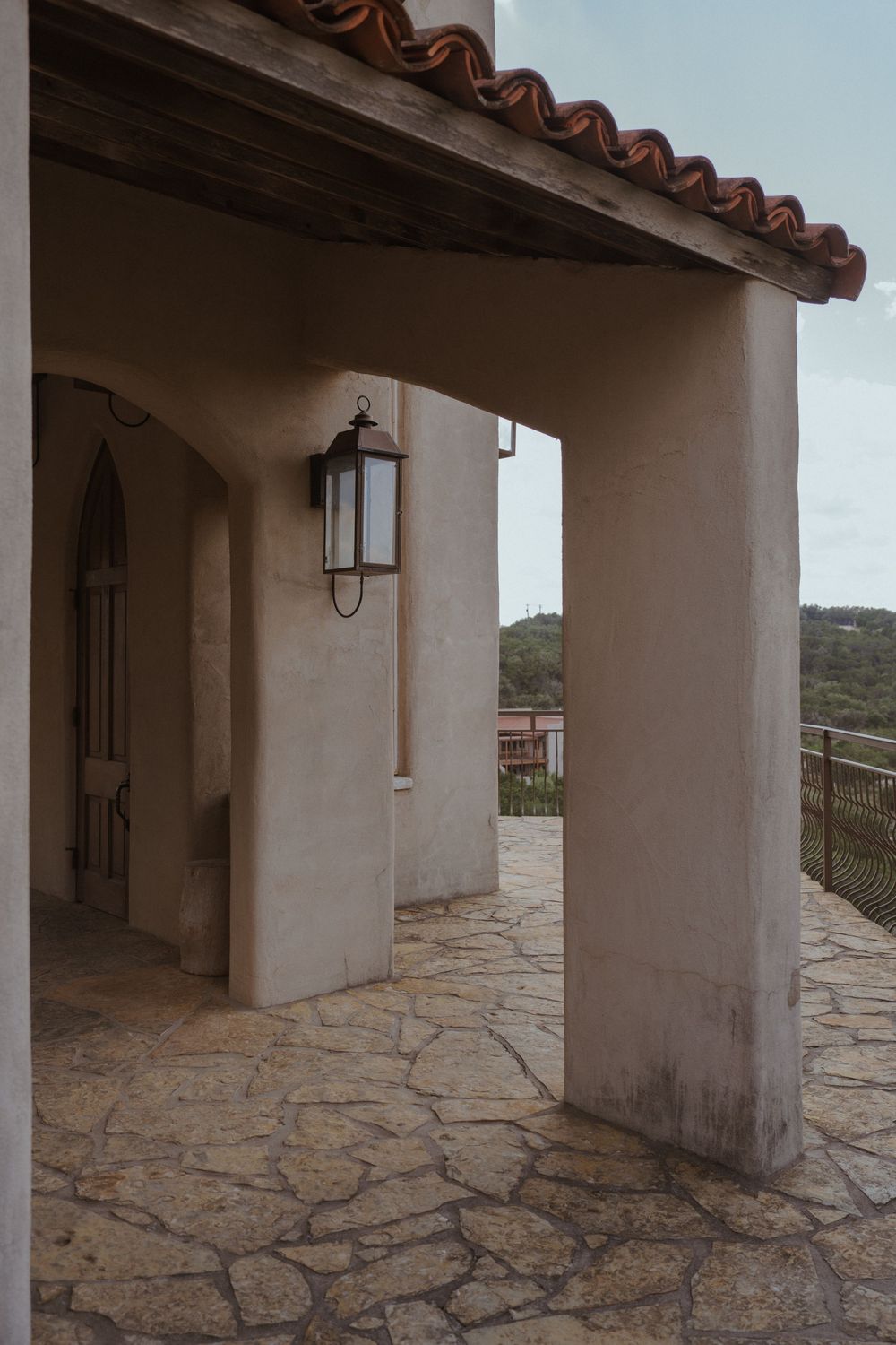 Spanish colonial style covered walkway with stone floor and terracotta roof tiles.