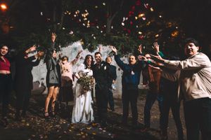 Wedding celebration at night with guests throwing confetti around the newlyweds.