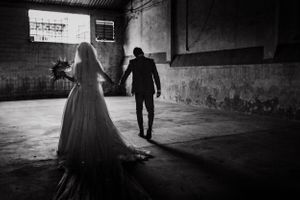 Silhouette of a couple walking in a dark industrial space with dramatic lighting.