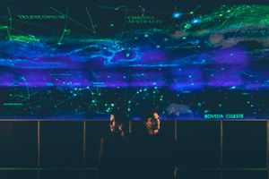 DJ performers silhouetted against vibrant blue lighting effects at a nighttime electronic music event.