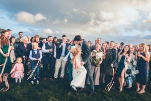 Large group gathered outdoors for celebration on grassy hillside.